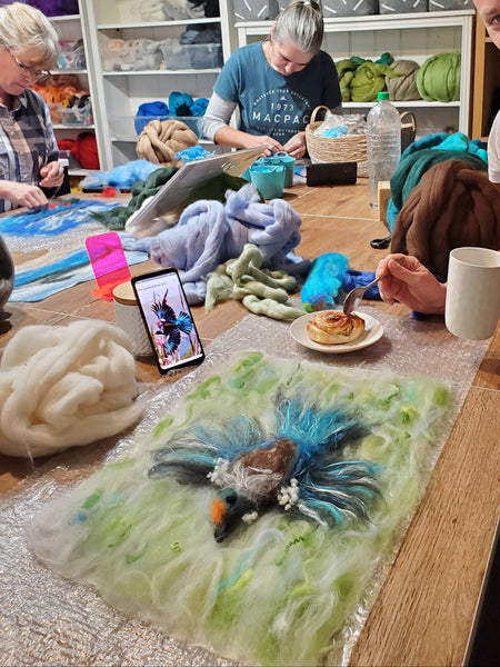 workshop with wool, theme birds, people standing around a table.