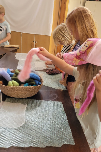 Children are creating wool art during the school holiday, items on a table.