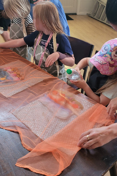 Children painting with wool in a classroom setting