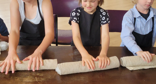 Children and adults participating in a craft activity at a table.