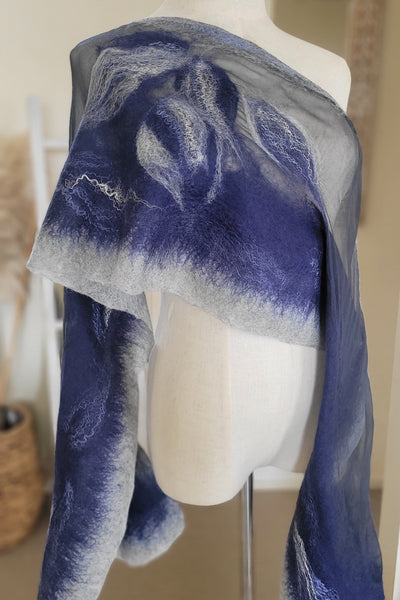 Blue and light grey scarf draped over a mannequin head with a neutral background