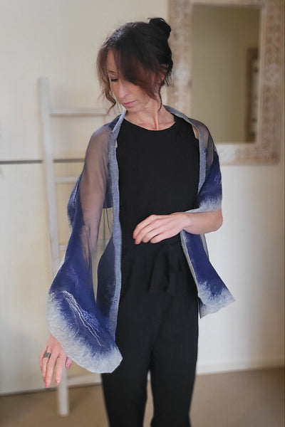 Person wearing a black outfit with a blue nuno felted scarf in an indoor setting