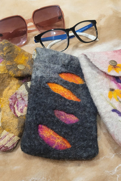 Colorful felt pouches with embroidered designs on a textured surface