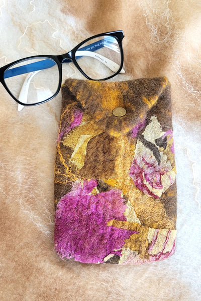 Floral-patterned glasses case with glasses on a textured surface