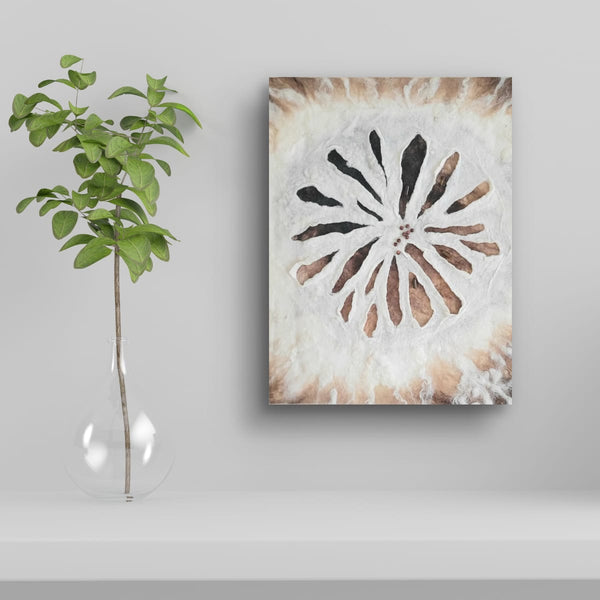 Decorative textured wall art with a flower design on a white wall beside a plant.