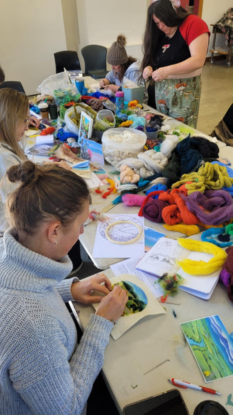 People engaged in a felting workshop with Vesu arts and crafts at a table with various materials and supplies.