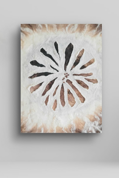 Decorative wall art with a flower design on a white wall next to a plant.