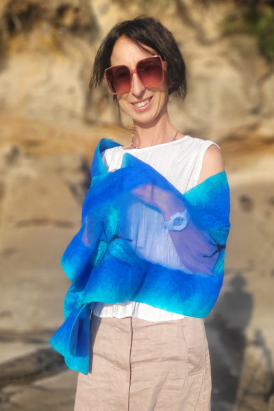 Person wearing sunglasses and a blue garment in a natural setting