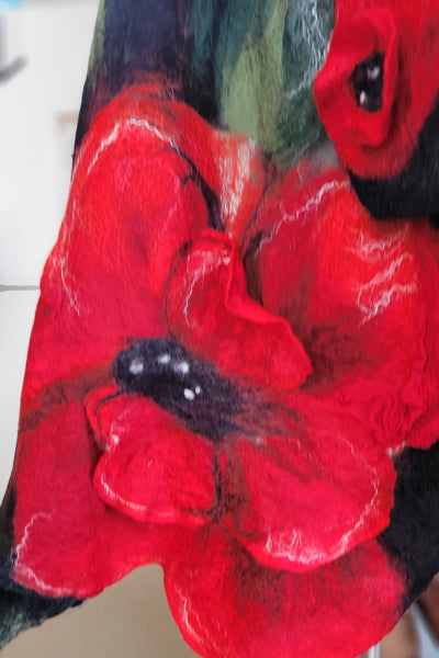 Close-up of a red flower with green leaves on a textured surface