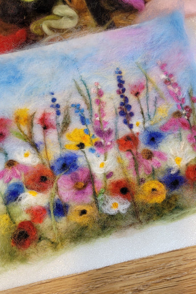 Colorful needle felted artwork on a wooden surface