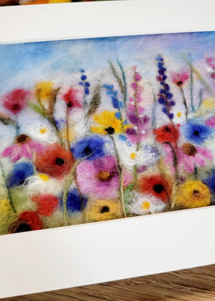 Felted artwork of colorful flowers on a wooden surface