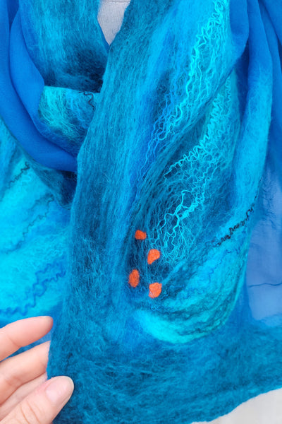 Close-up of blue textured felted with silk fabric with orange dots on a white background