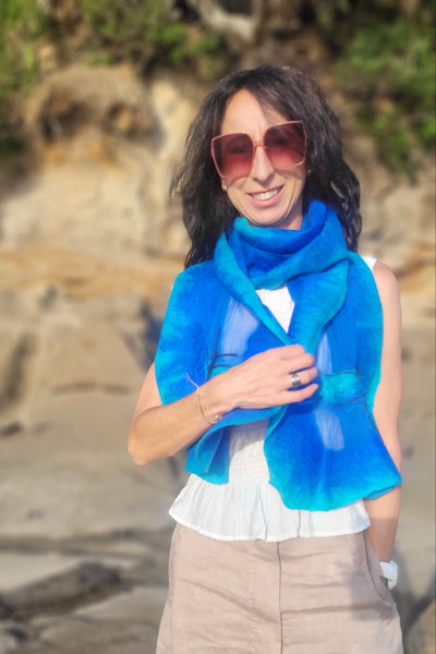 Person wearing a blue life jacket on a rocky shore