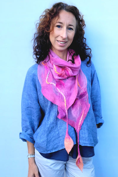 Woman wearing a blue shirt and pink scarf against a light blue background