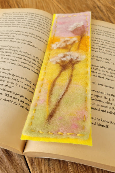 Decorative floral bookmark on an open book with a wooden surface background