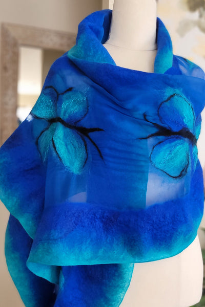 Blue scarf with black patterns on a mannequin against a neutral background