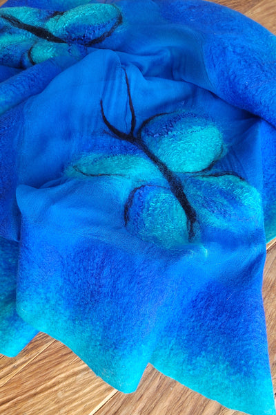 Blue textured fabric with leaf patterns on a wooden surface