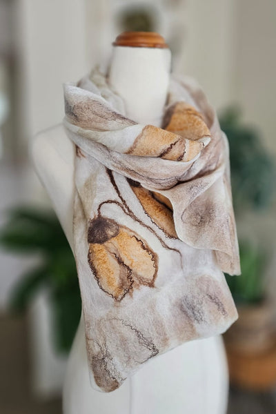 Scarf with autumn leaf pattern on a mannequin against a blurred indoor background