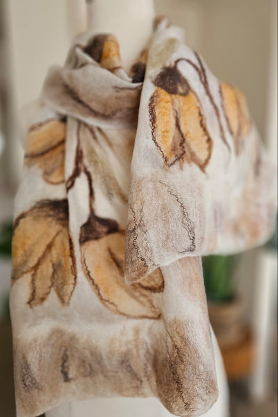 Scarf with leaf pattern draped over a mannequin against a blurred indoor background