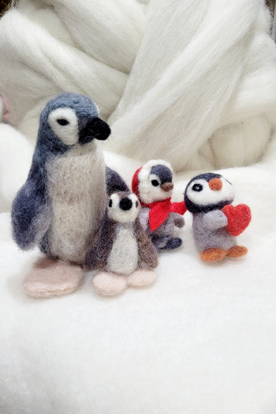 Felted penguin family with a parent and three children on a white background