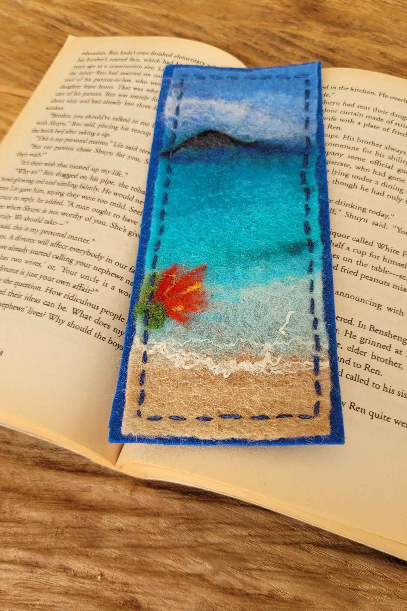 Decorative bookmark with an ocean and floral design on an open book