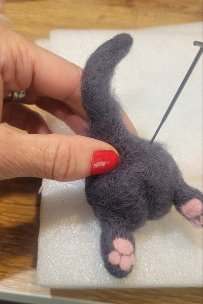 Hand holding a small felted toy on a wooden surface