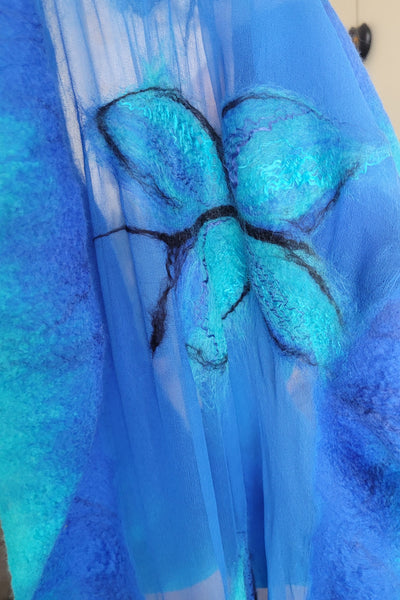 Close-up of blue fabric with a floral pattern, held by a gloved hand.