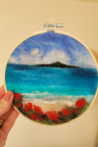 Round wall art with a colourful wool  fabric design held by a hand against a beige background