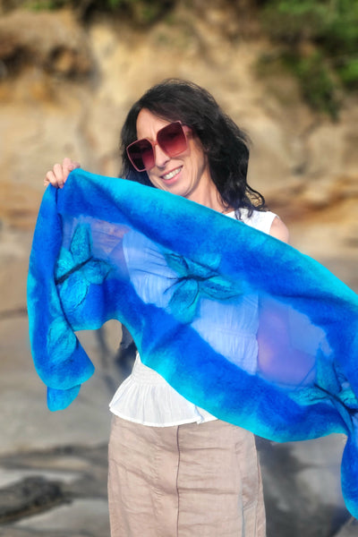 Woman holding a blue scarf with a blurred natural background