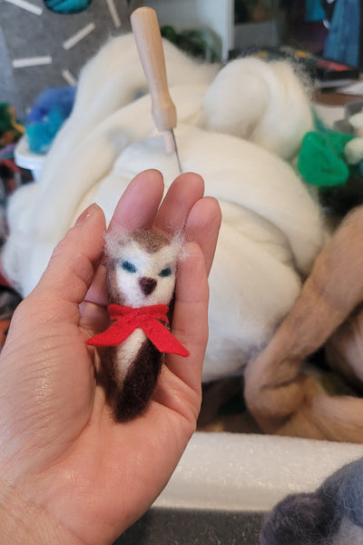 Small felted owl held in a hand with a blurred background