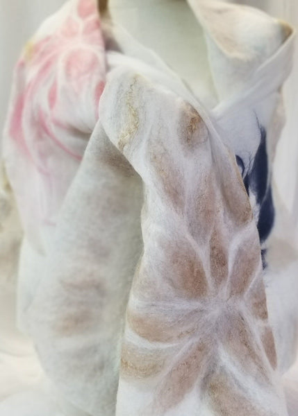 Close-up of a textured merino wool and silk shawl with floral patterns on a white background